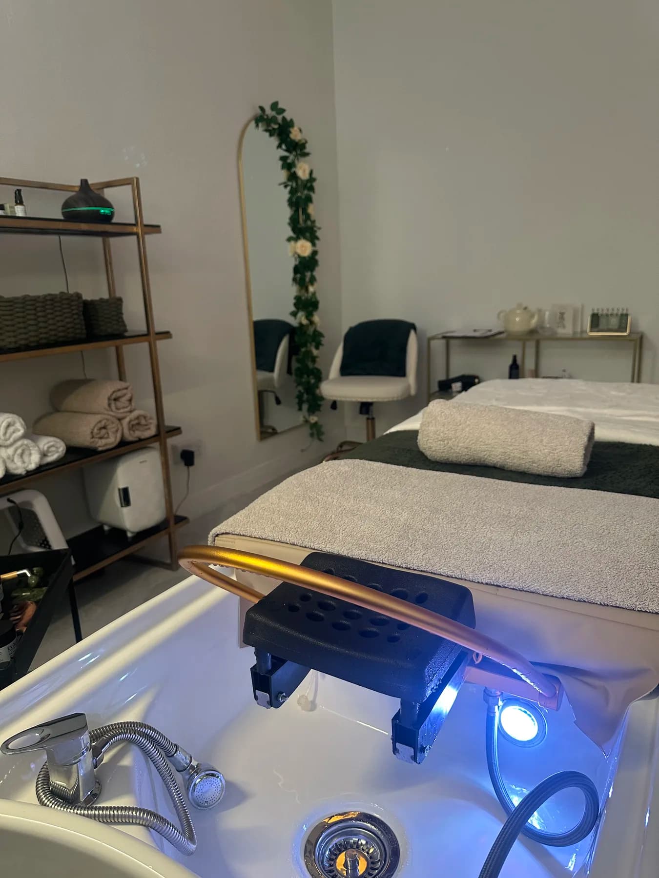 Treatment room with floral arch and gold shelving